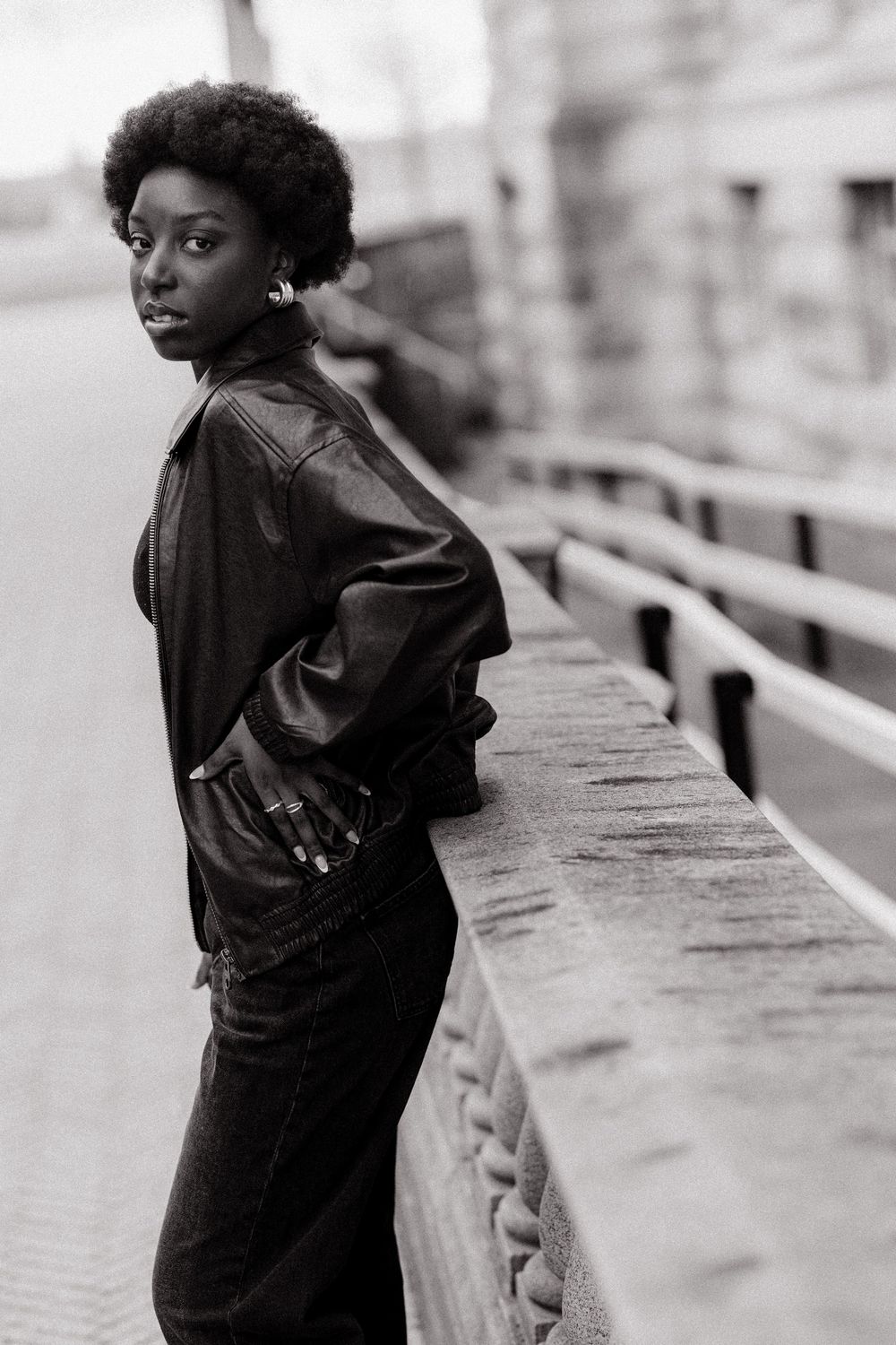 A person in a black coat leans against a concrete wall in a series of artistic black and white photographs.