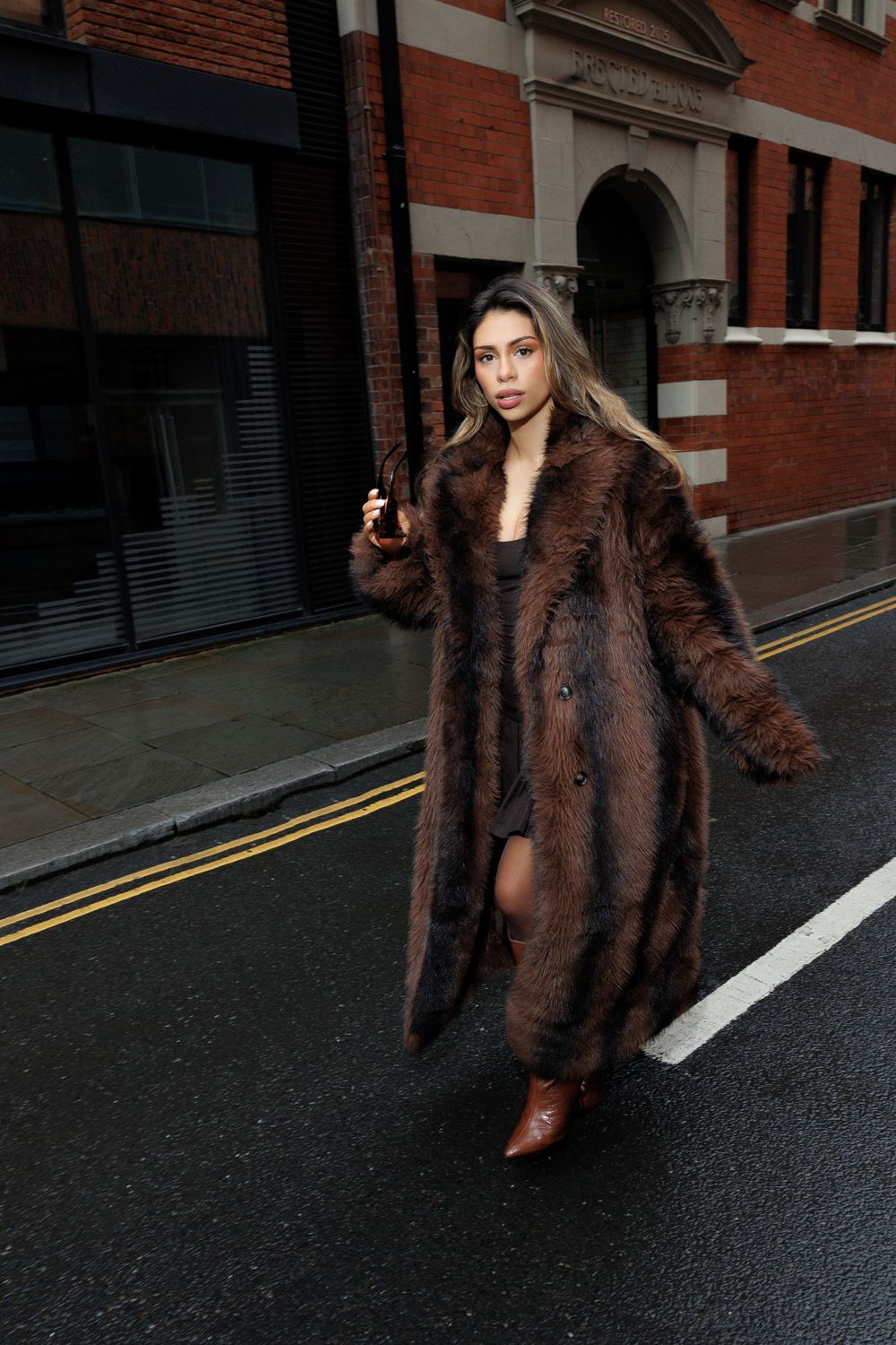 Fashion photography series showing a brown fur coat styled against industrial brick architecture and city streets.