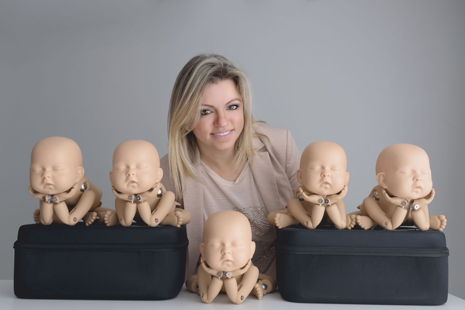 A row of realistic baby doll heads displayed on a dark surface showing different angles and positions. Paloma Schell