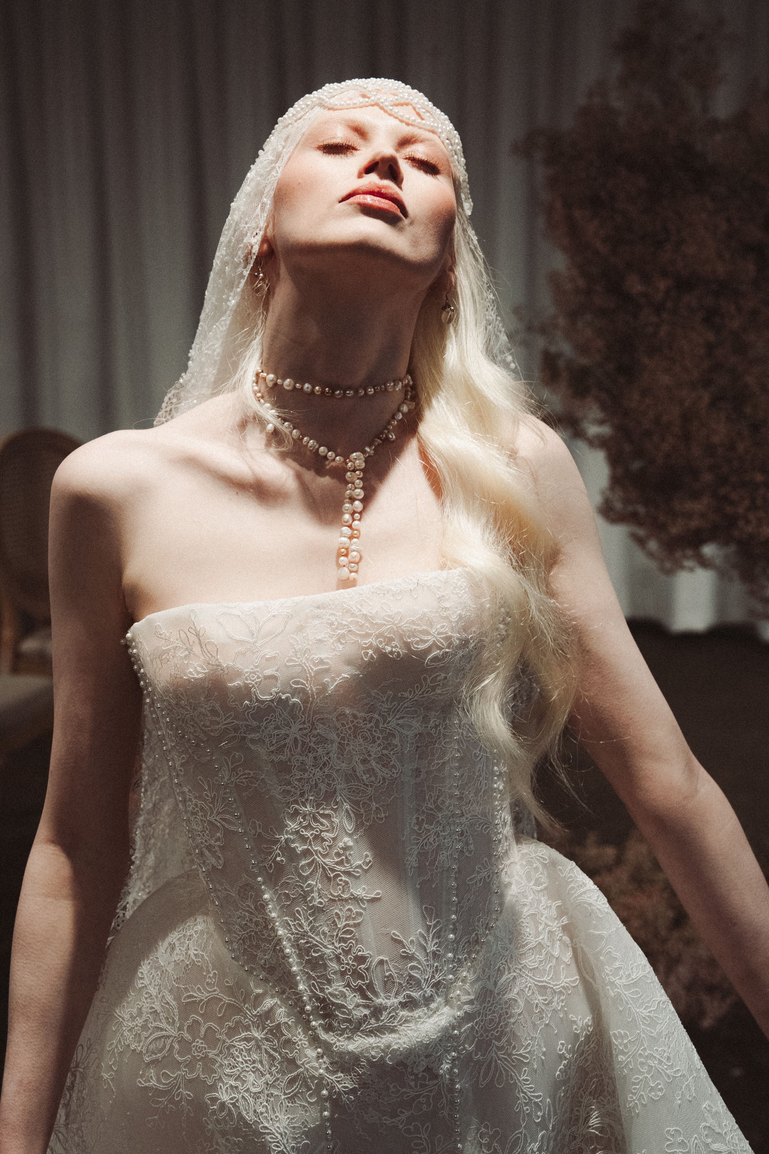 A series of artistic fashion photos showing a model in a white lace dress with a pearl necklace against a dark background.