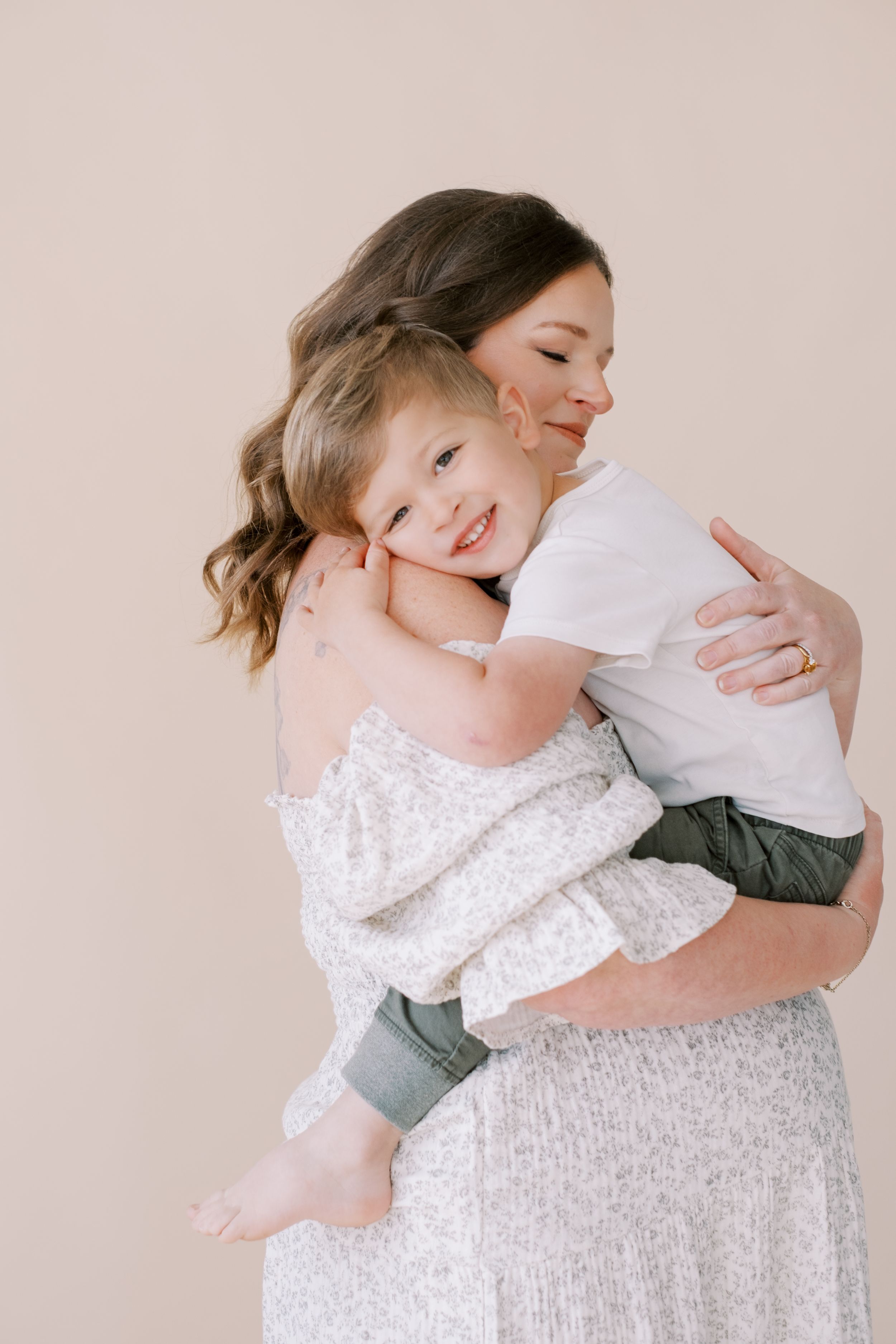A series of tender embrace photos showing a mother and child in white and grey tones against a neutral backdrop.