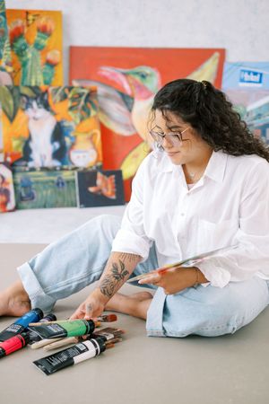 Person in white shirt lying on floor with remote controls arranged in artistic composition.