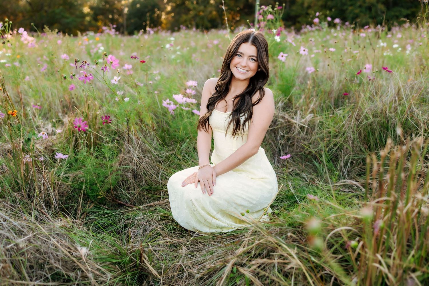 A long white dress stands out against a dreamy meadow filled with pink wildflowers at golden hour.