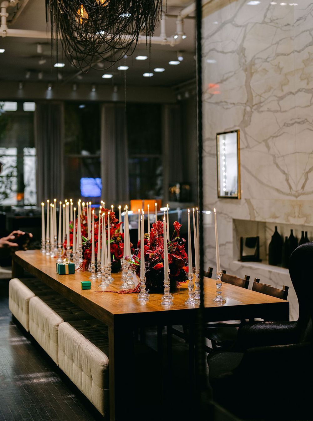 Modern restaurant interior with sleek white bench seating and wooden tables illuminated by warm overhead lighting.