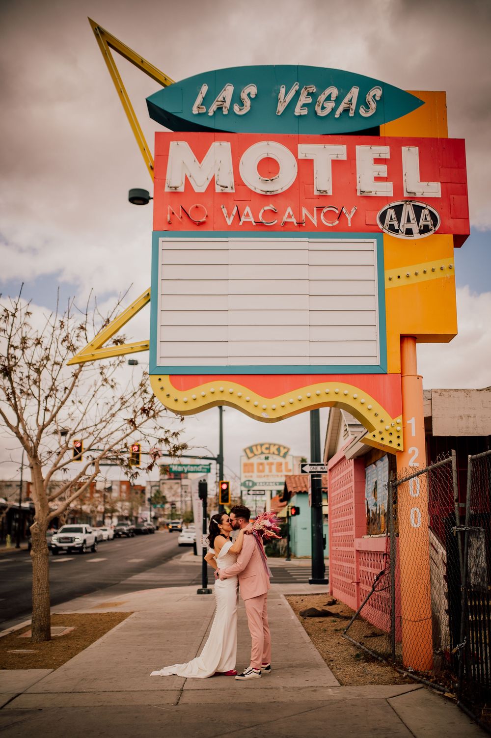 Retro Las Vegas motel sign with blank marquee stands above a street corner on a cloudy day.