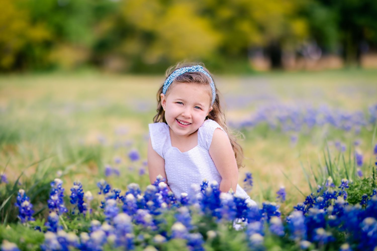 Child sitting in blooming bluebonnets during a Central Texas spring mini session with natural light photography.