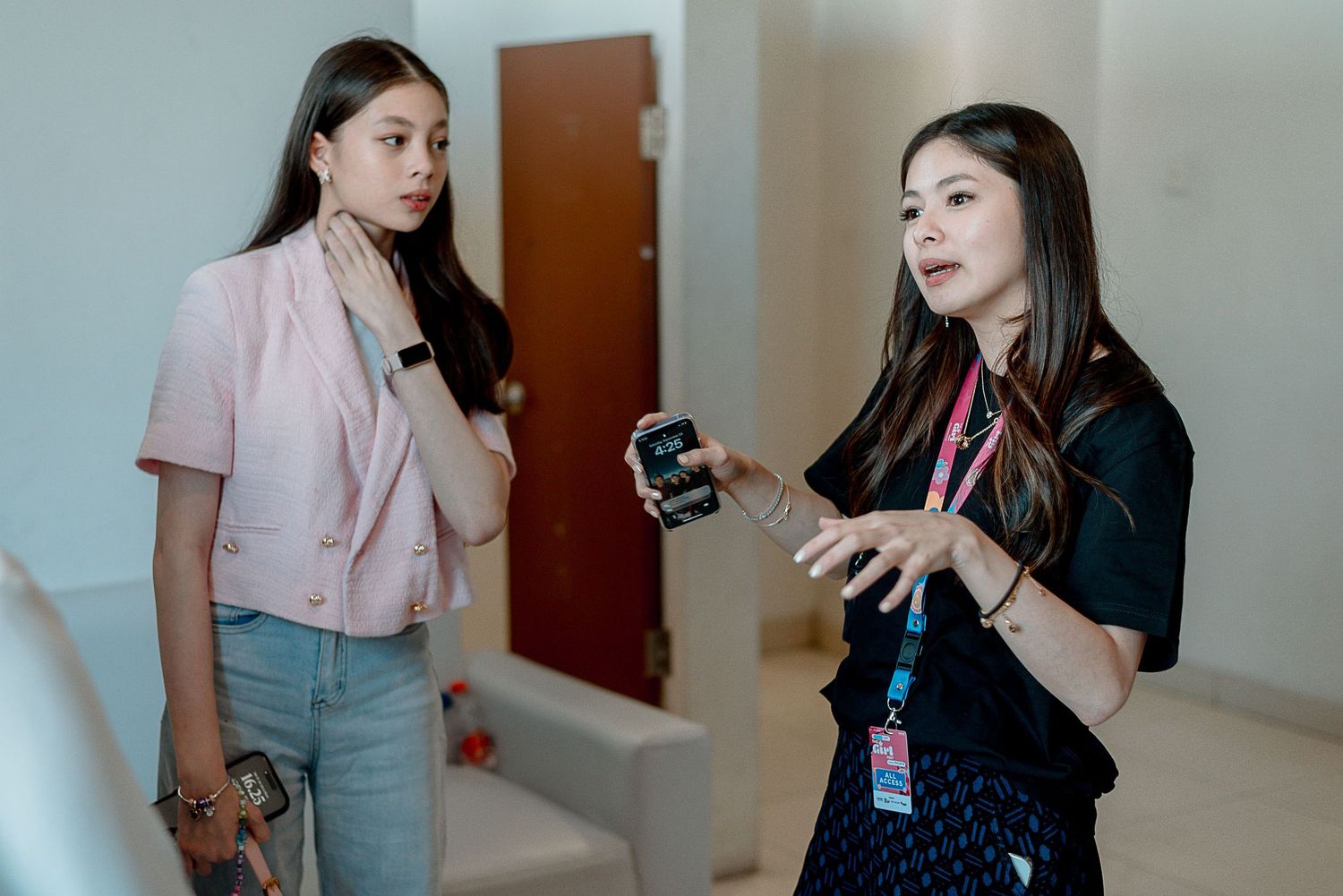 Two colleagues in casual business attire having a conversation in an office hallway.