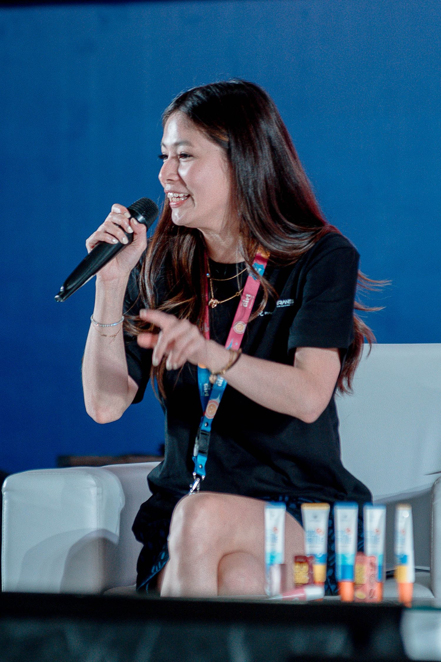 A performer in black clothing sings emotionally into a microphone against a blue background during a live performance.