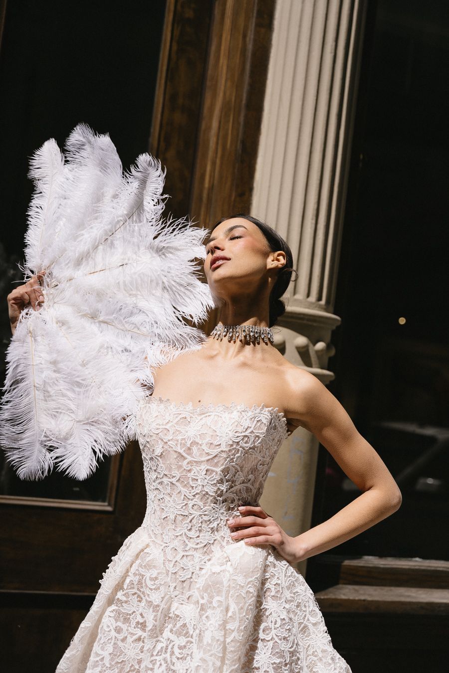 A dramatic fashion photo series showing a white feathered wedding gown with lace details in an elegant pose.