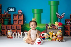 Super Mario themed first birthday setup with green pipes and plush characters.