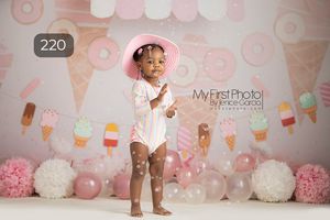 Ice cream themed birthday setup with pink decorations and pom poms.