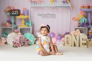 Pastel birthday setup with floral arch, balloons and ONE letters.