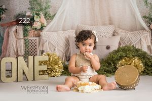 Boho themed cake smash setup with macrame backdrop and gold accents.