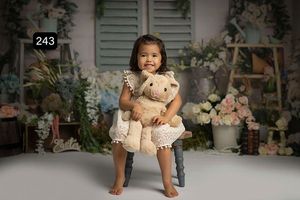 Cottage garden themed photo set with white shutters and climbing floral arrangements.