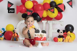 Mickey Mouse themed birthday setup with red, yellow and black balloon arch decorations.