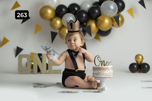 First birthday celebration setup with black and gold balloons and cake.