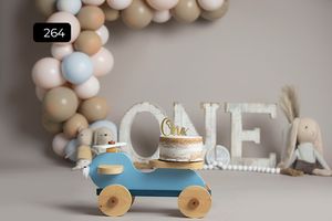 Vintage inspired first birthday setup with toy car and balloon arch in neutral tones.