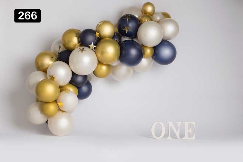 Elegant balloon arch in gold, navy blue and white with 'ONE' text display against grey background.