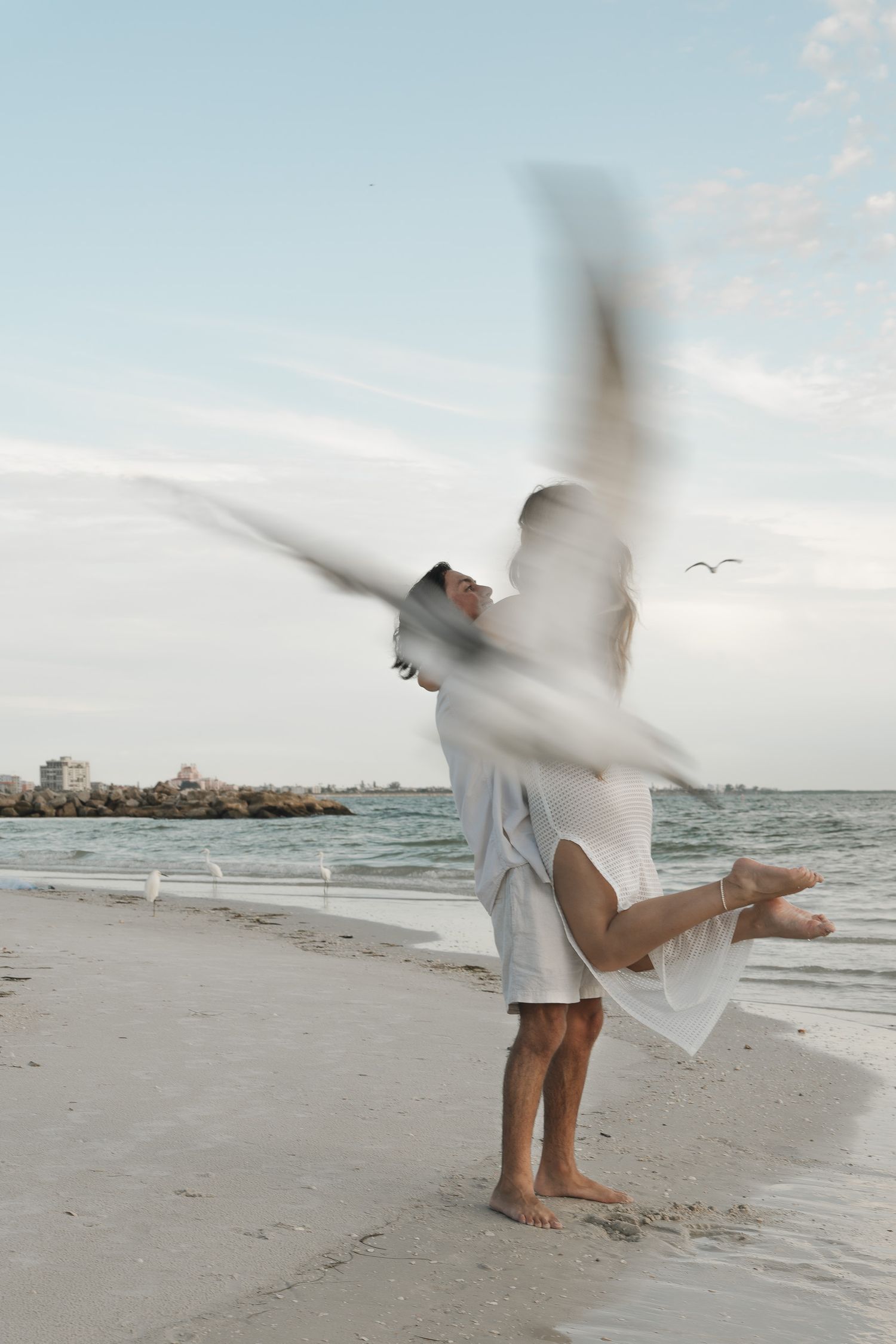 A romantic couple embraces while standing in water during an intimate photoshoot at sunset.