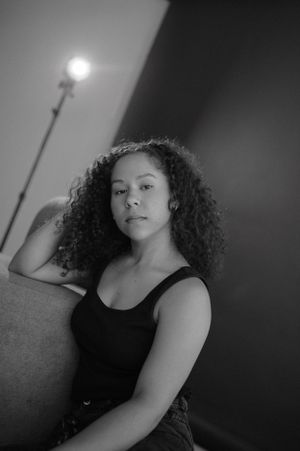 Studio portrait with visible lighting equipment capturing casual pose against dark background.