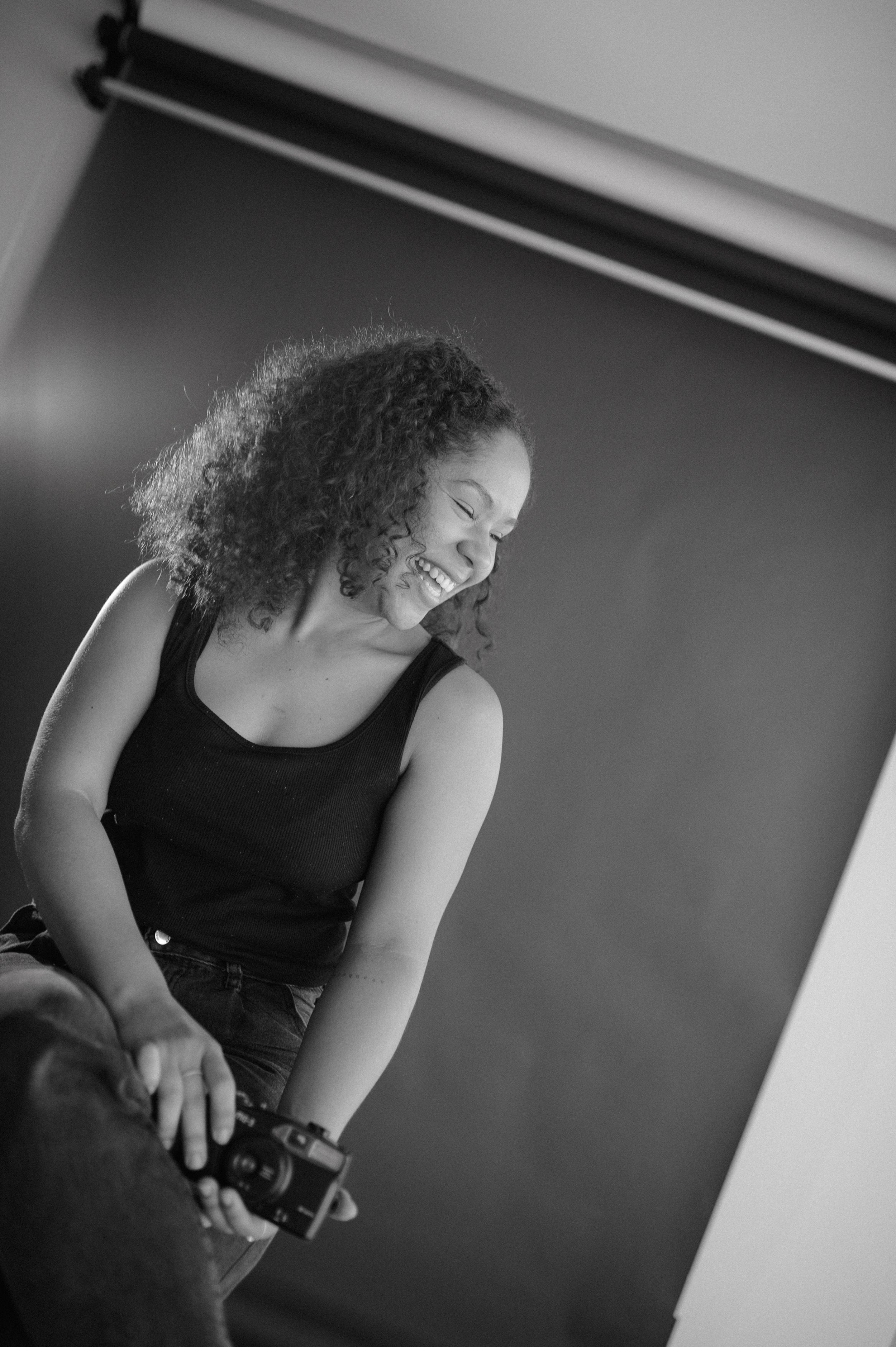 Candid black and white studio portrait showing genuine laughter and natural expression.