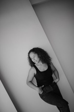 Black and white portrait of person in casual attire against geometric wall background.