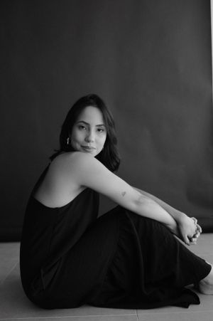 Monochrome portrait of someone in a black dress sitting on the floor with artistic lighting.