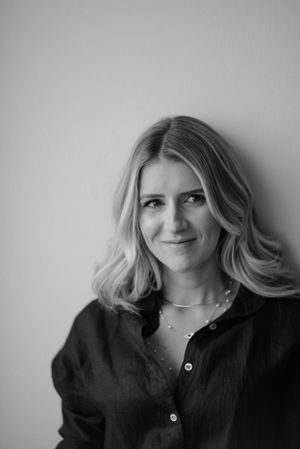 Professional headshot in black and white featuring natural smile and casual black button-up shirt.