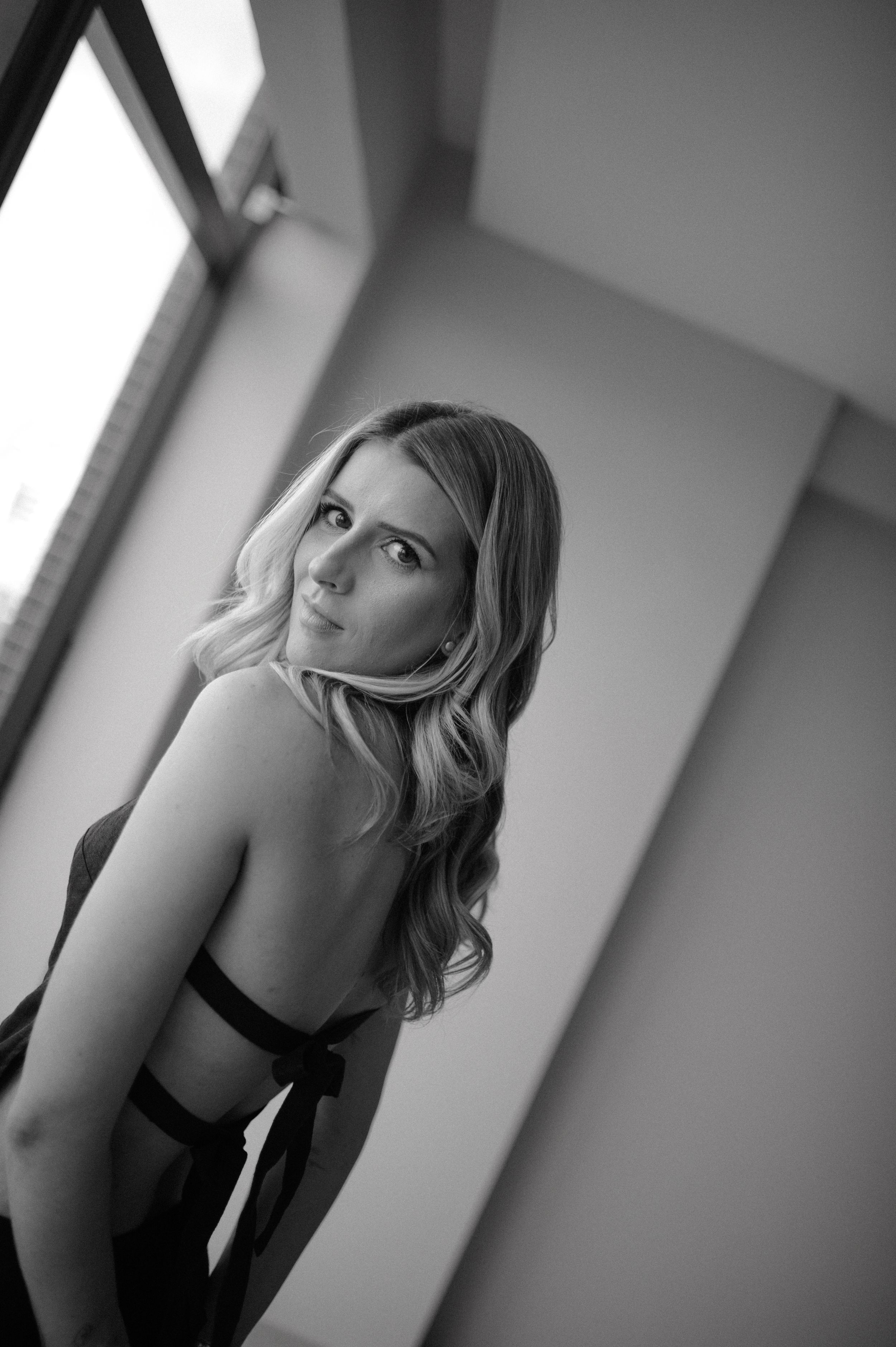 Glamorous black and white portrait featuring elegant pose near window light.