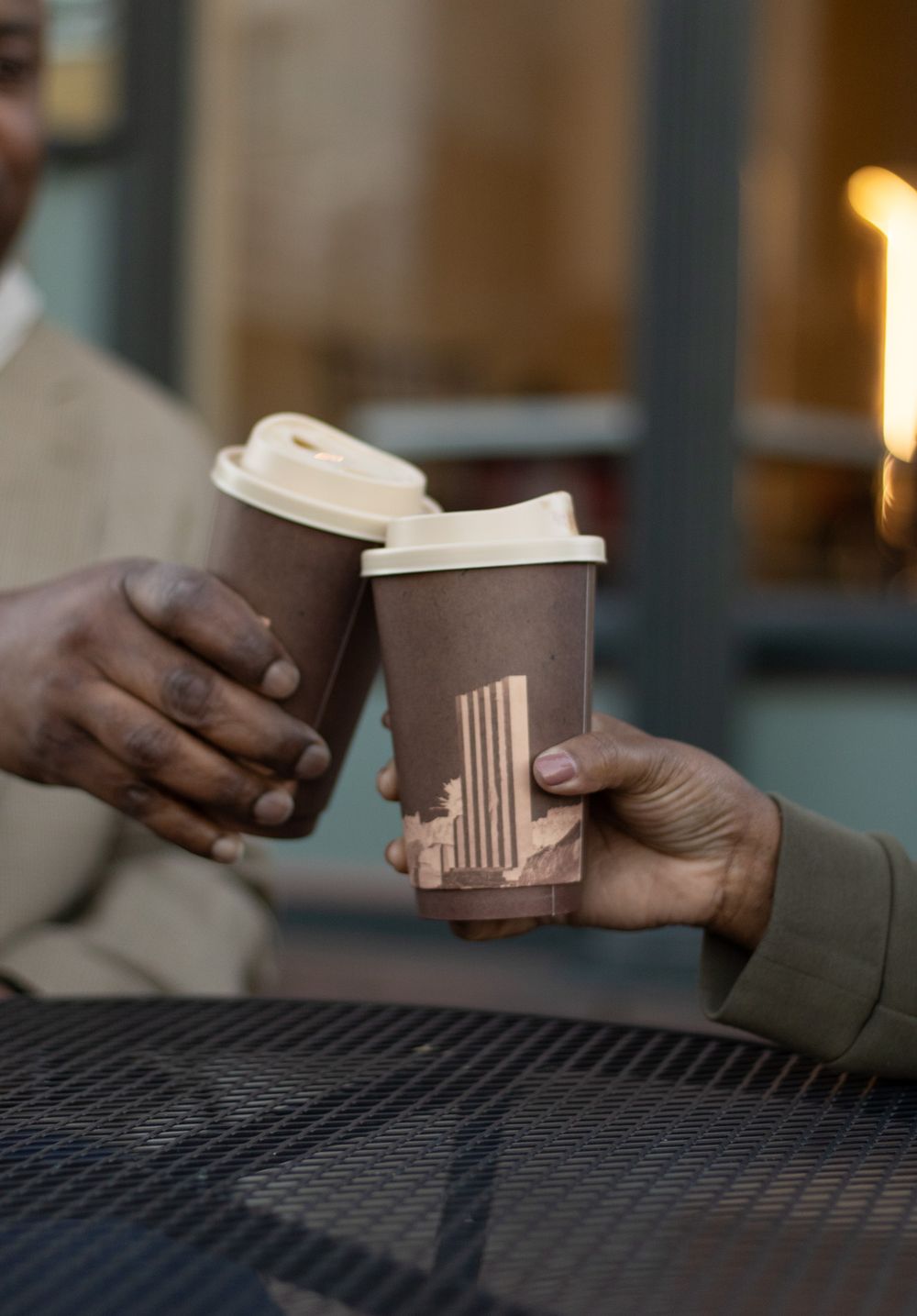 Two hands exchanging coffee cups in a dimly lit setting.