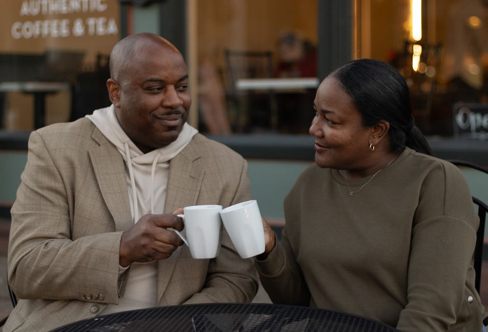 Two people sharing coffee and conversation at a cafe counter.