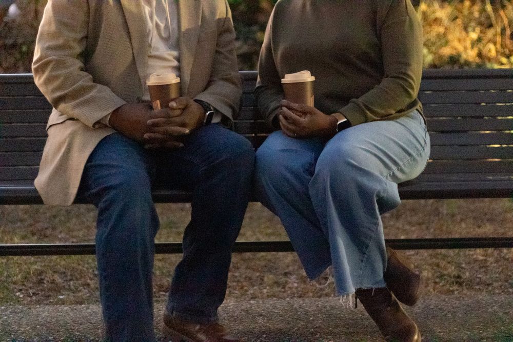 Two people sitting together on an outdoor bench during autumn.