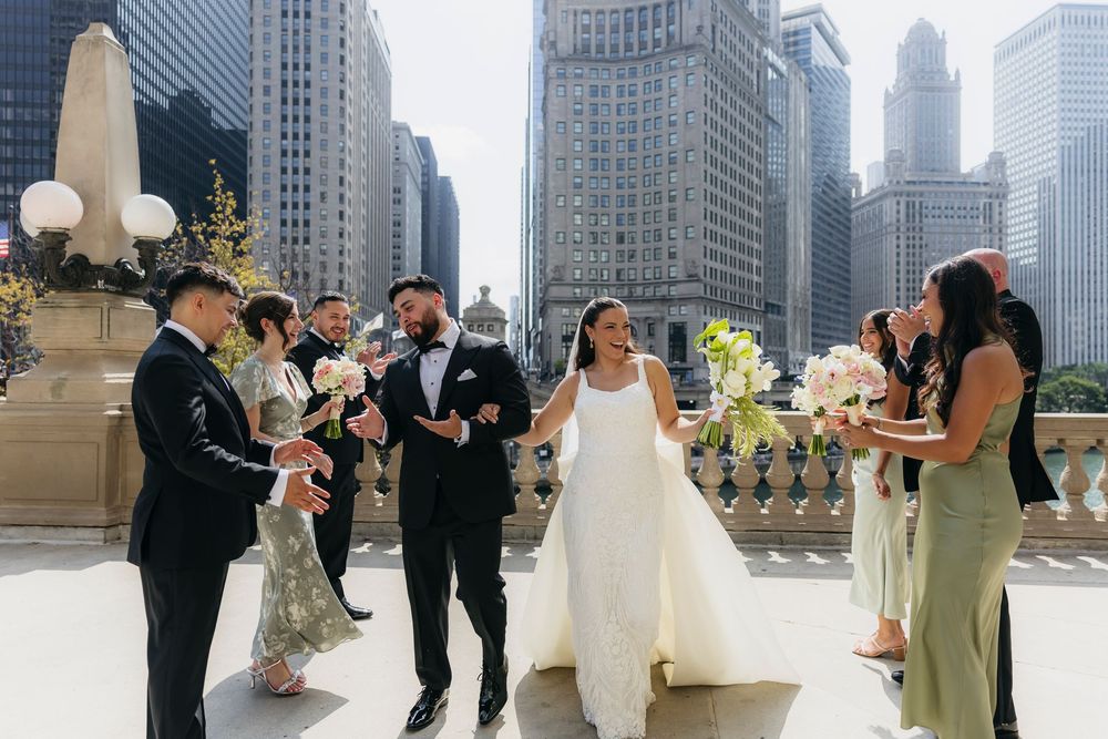 A wedding party candidly walks together in front of Chicago skyscrapers in a city setting during a sunny day.
