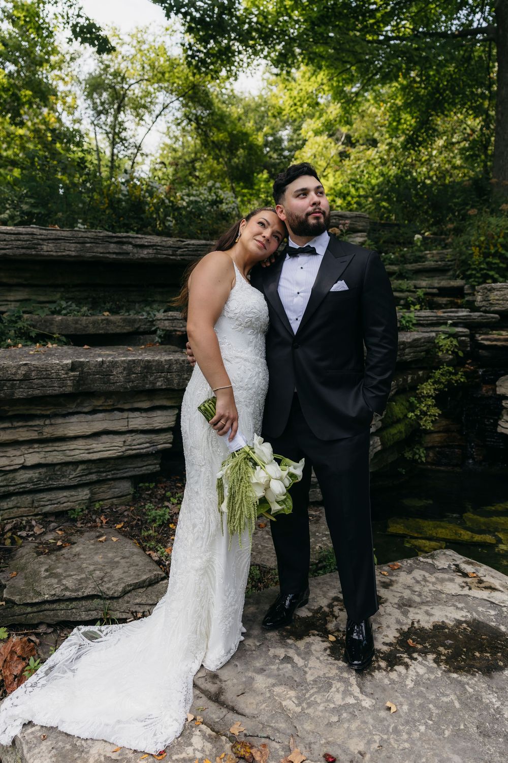 A couple shares a romantic moment against a rustic stone wall backdrop during their outdoor wedding session in Chicago Lily Pool