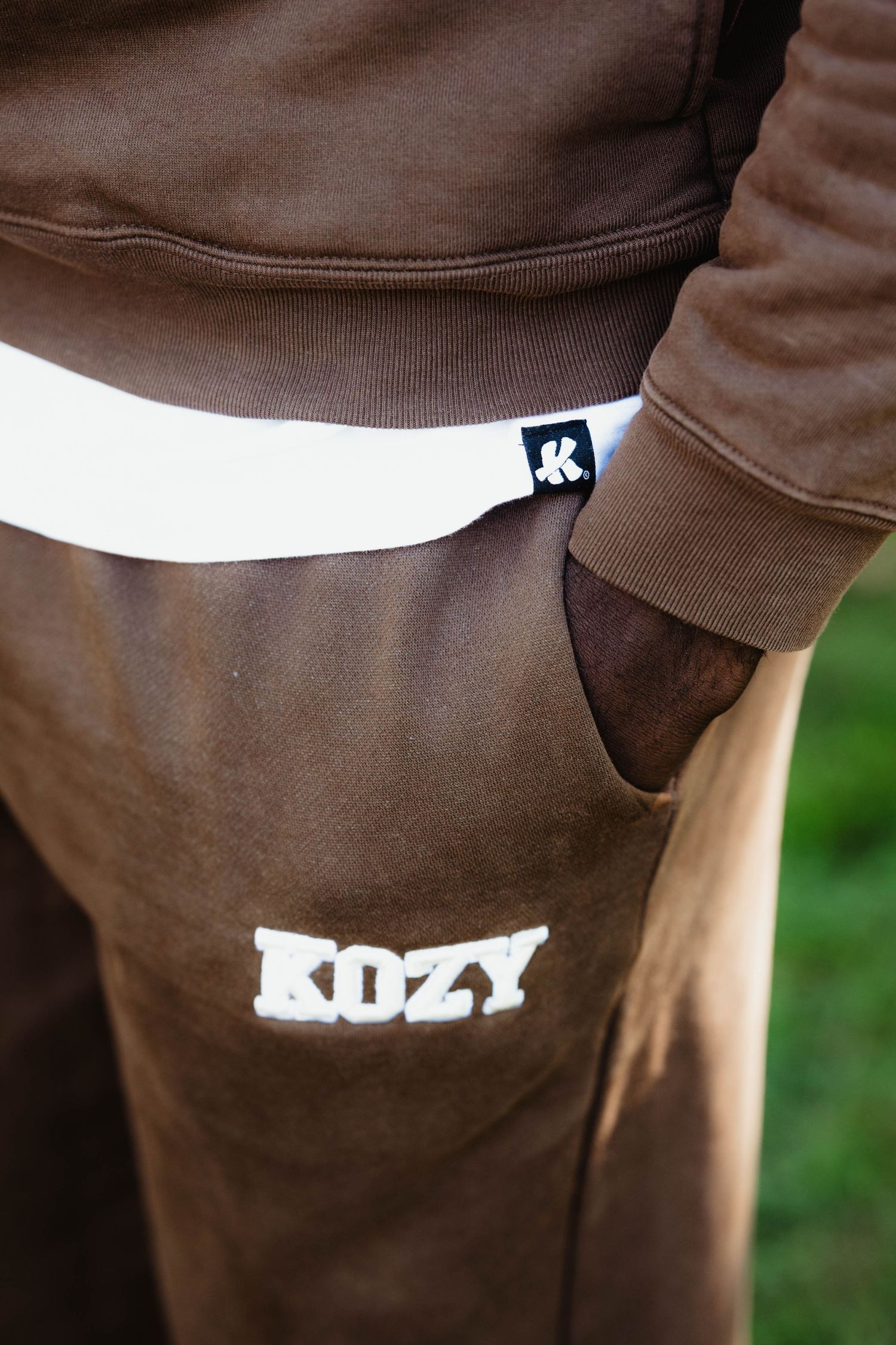 Close-up view of brown clothing with white text detail showing partial logo or branding elements.