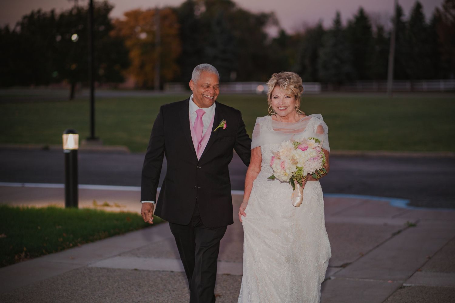 Evening outdoor wedding ceremony with romantic lighting and natural landscape.