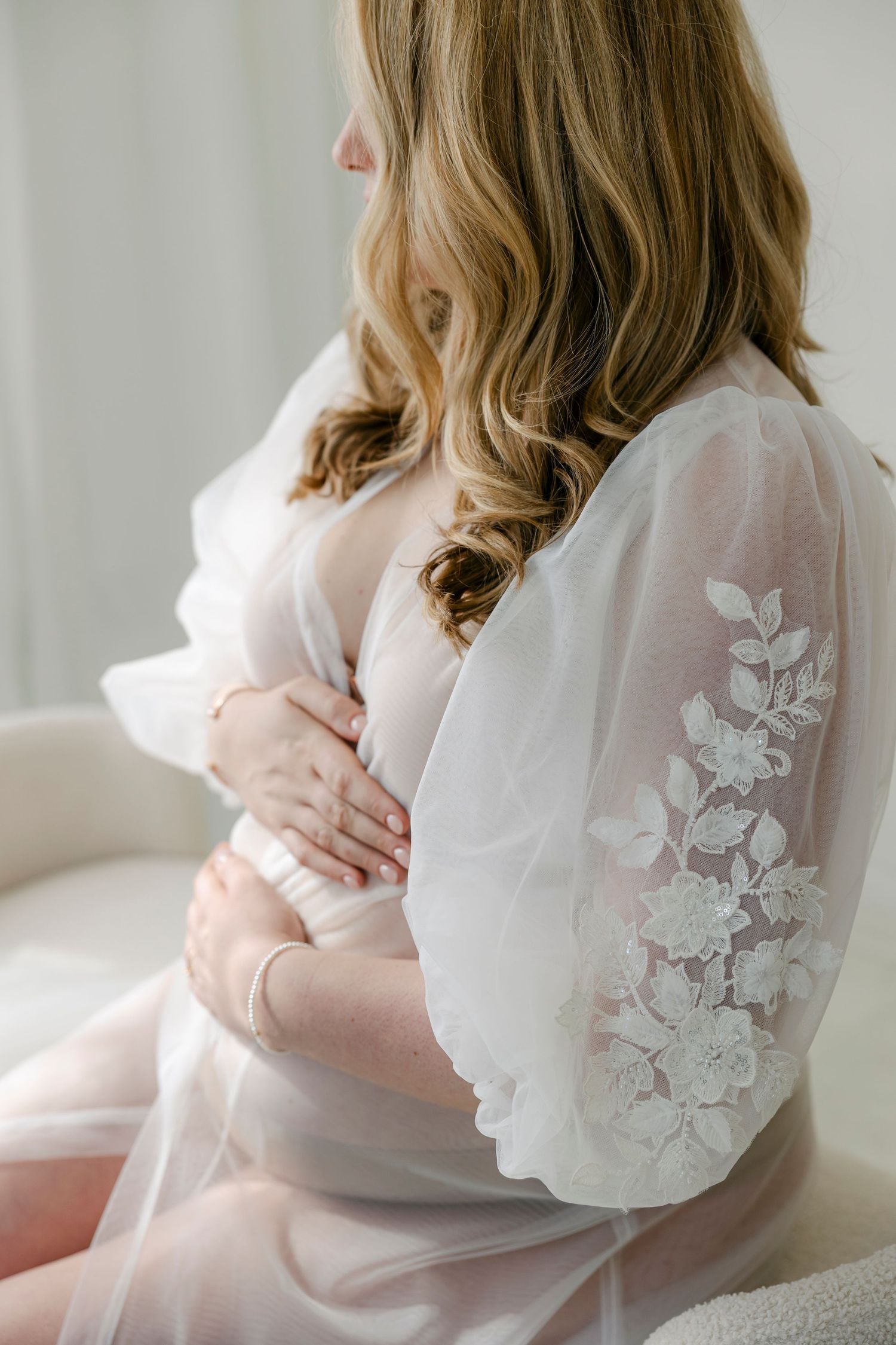 Delicate white lace robe with floral embroidery details on sheer sleeves, photographed in soft natural light.