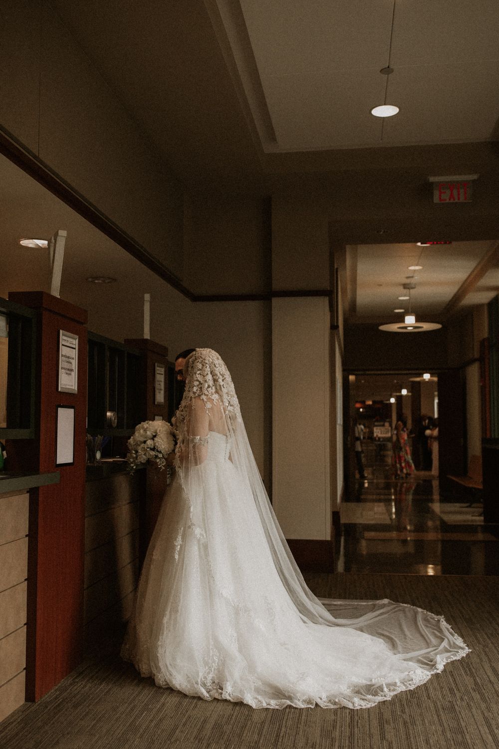 A series of elegant wedding dress shots showing a flowing white gown and veil in a dimly lit hallway.