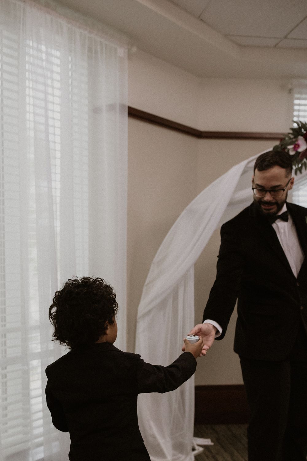 A couple shares a playful moment with a flowing white veil during their indoor wedding celebration.