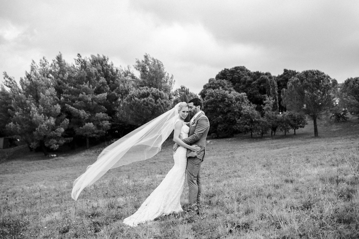 Bride and groom embracing in Provence field with flowing veil