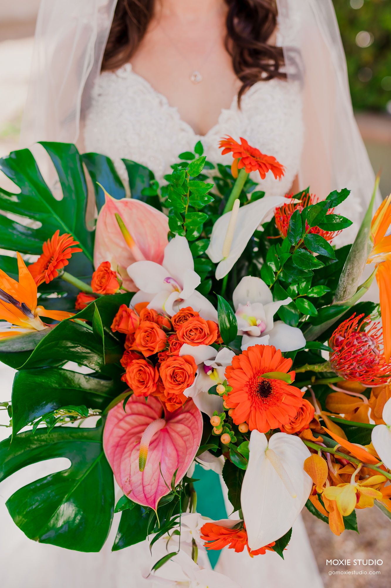 Vibrant tropical wedding bouquets featuring orange roses, gerbera daisies, anthurium, and monstera leaves create a stunning display.