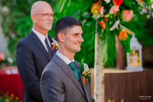 Wedding party members stand together outdoors during a garden ceremony with lush greenery and floral decorations.