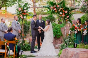 A romantic outdoor garden wedding ceremony with floral decorations and guests gathered under natural sunlight.