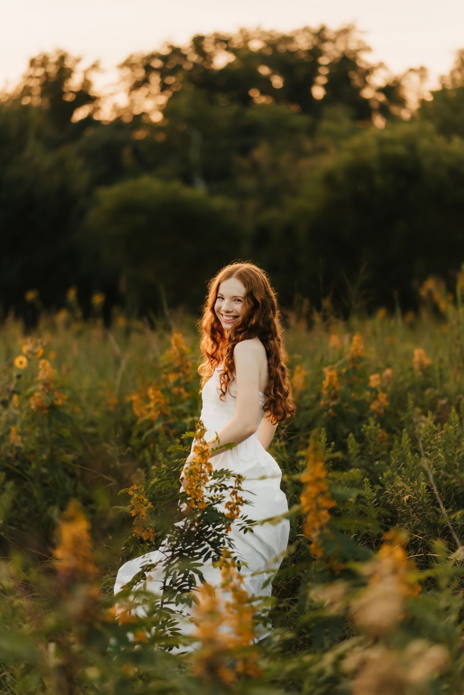 Senior girl laughs in field during senior photo session