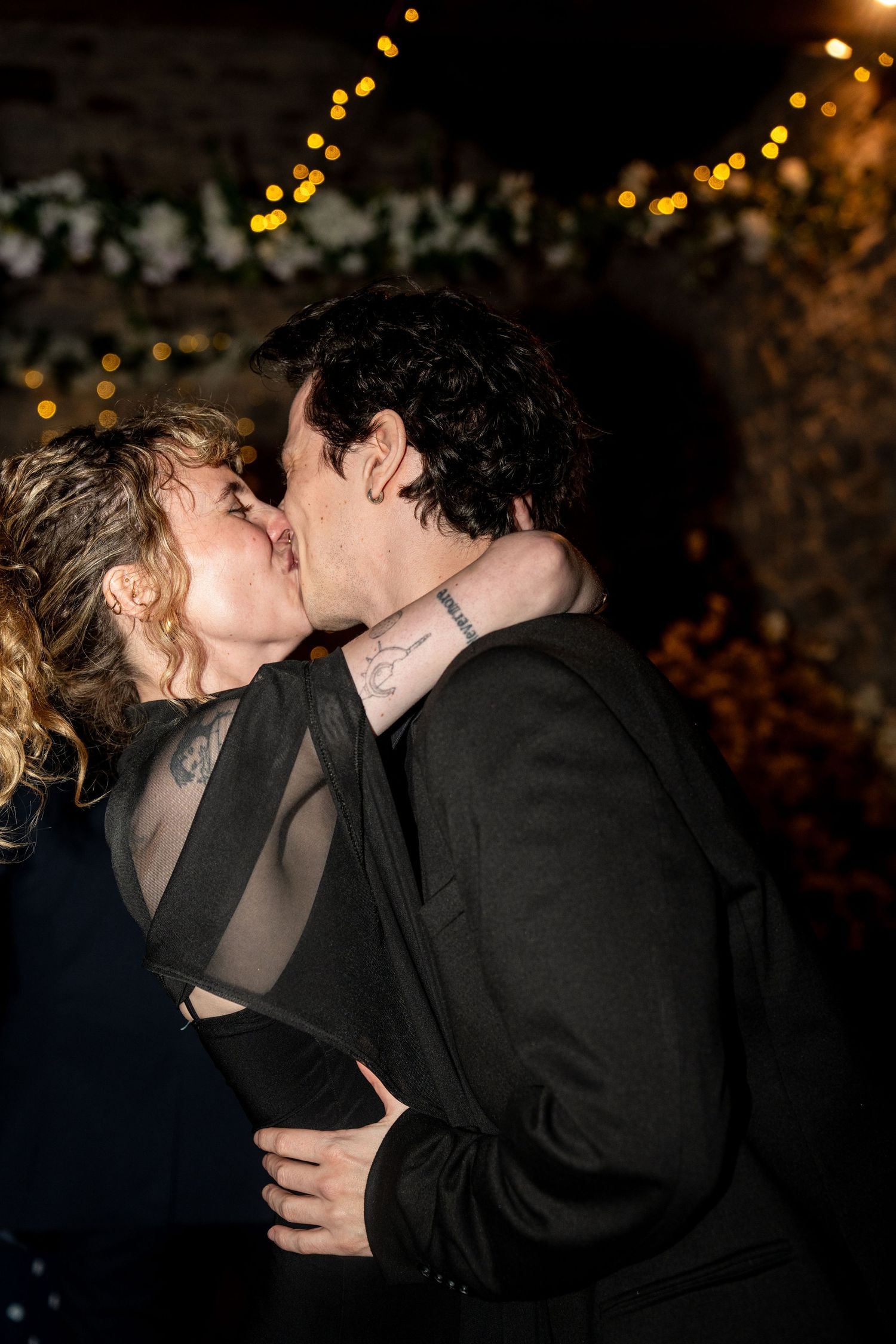 A couple shares a romantic kiss at night under twinkling lights in a series of candid moments.