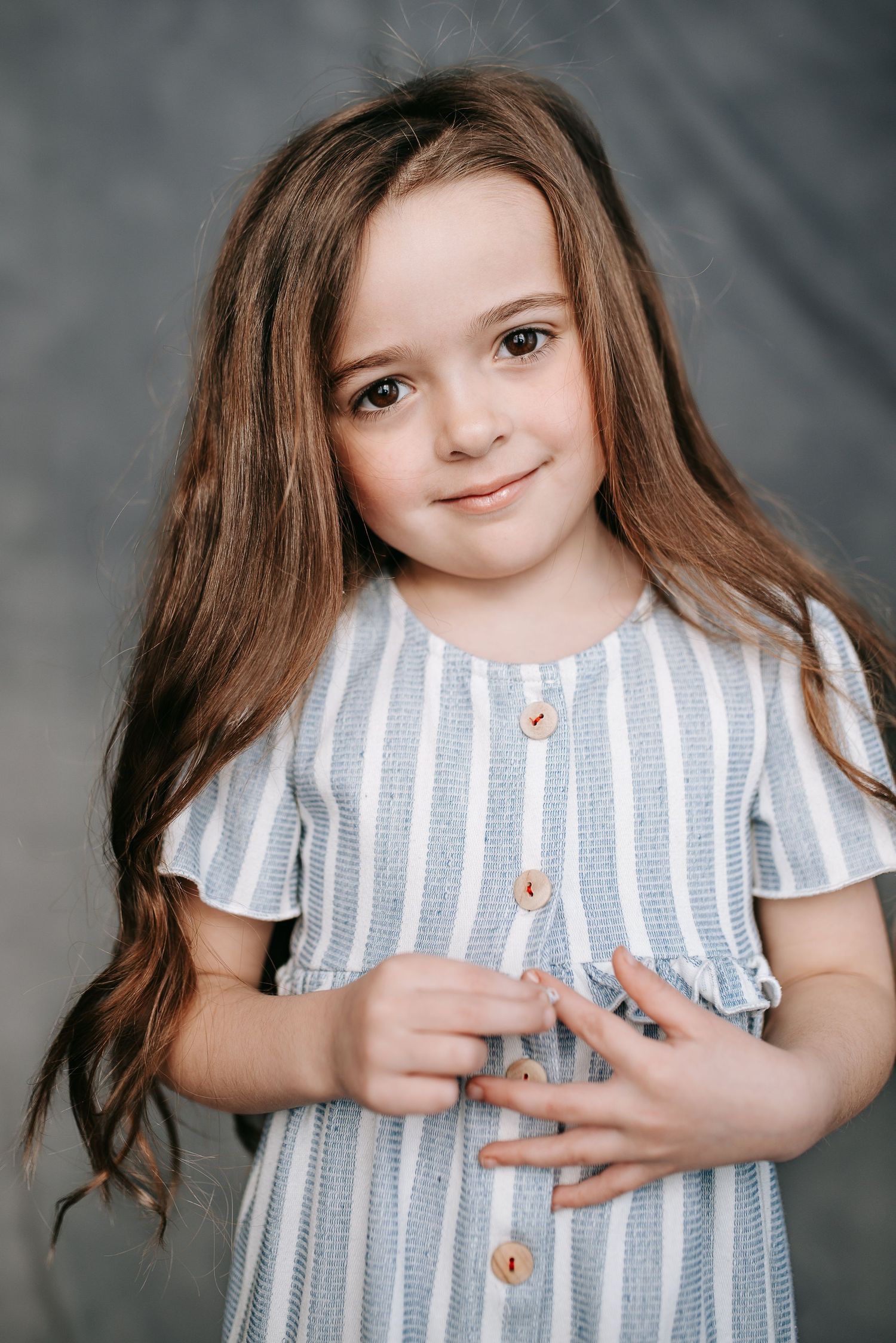 Studio portrait in blue and white striped dress with natural lighting.