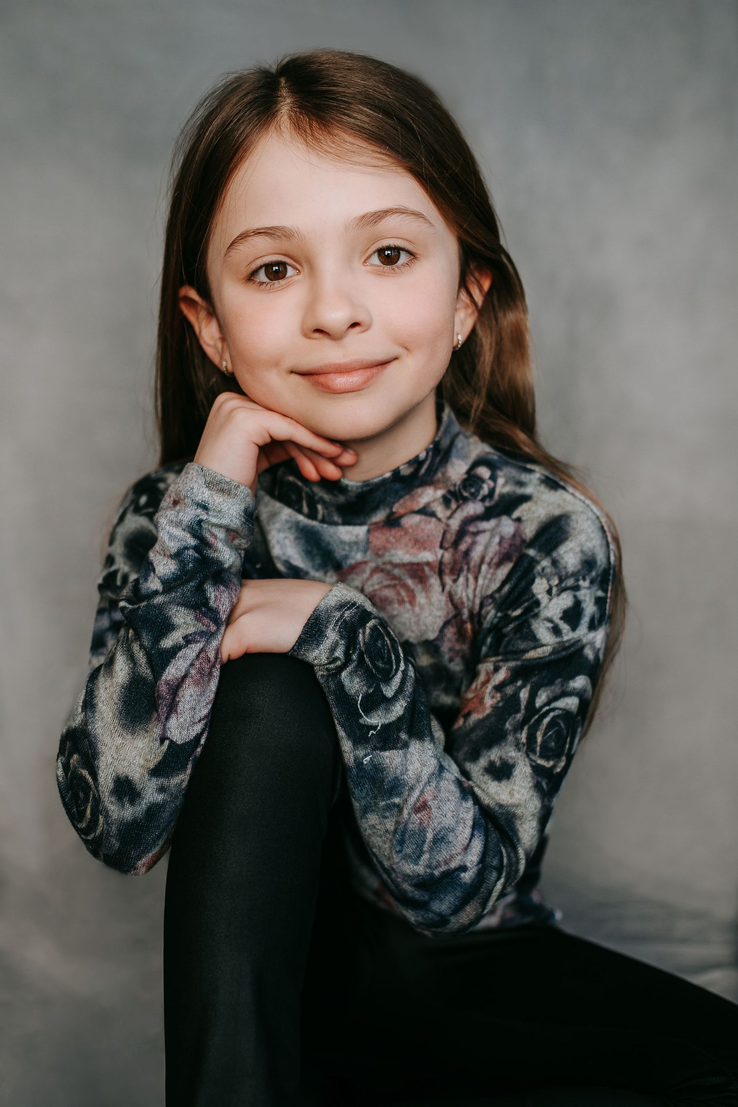 Studio portrait wearing tie-dye sweatshirt against grey backdrop.