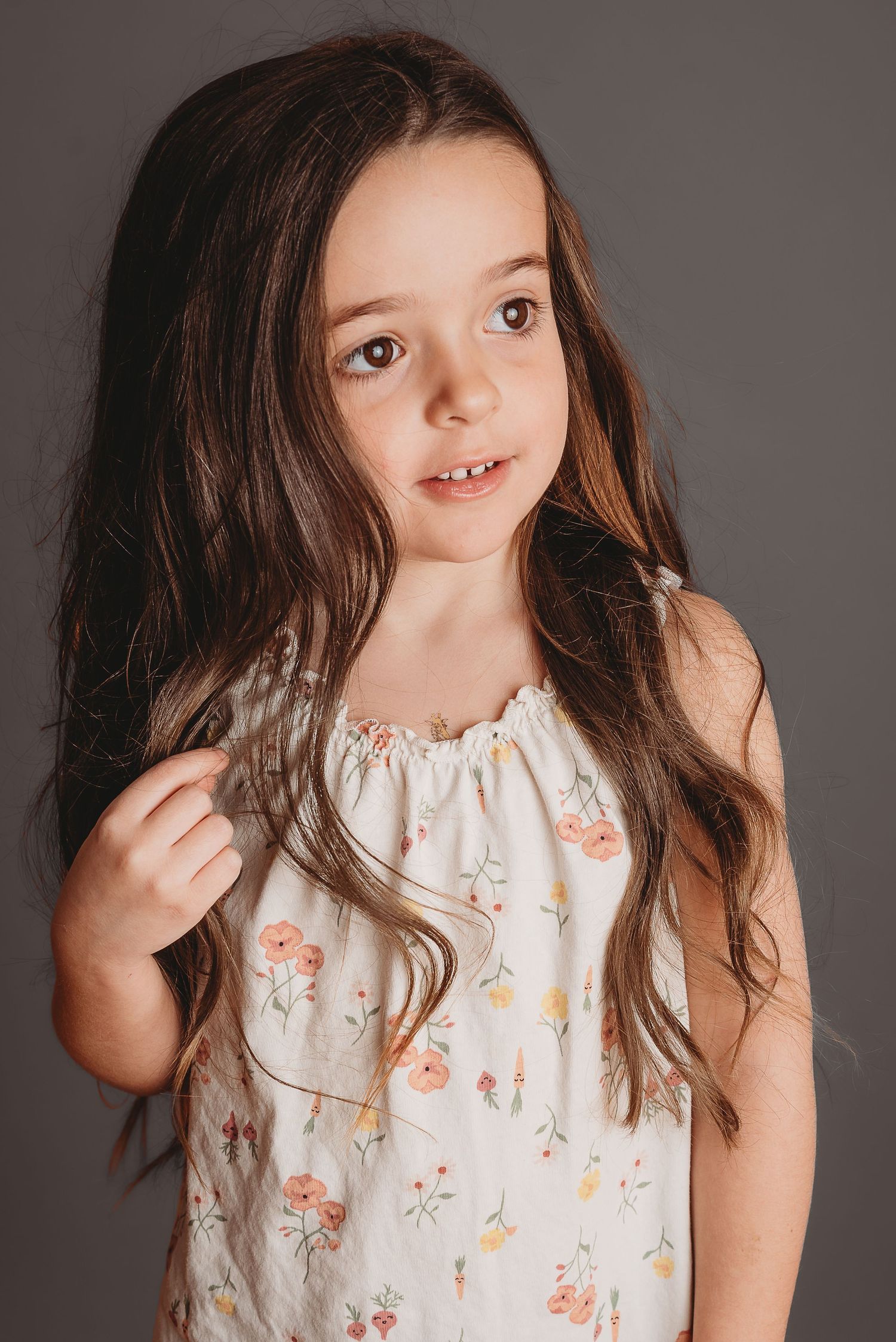 Portrait in floral summer dress with long hair against dark background.