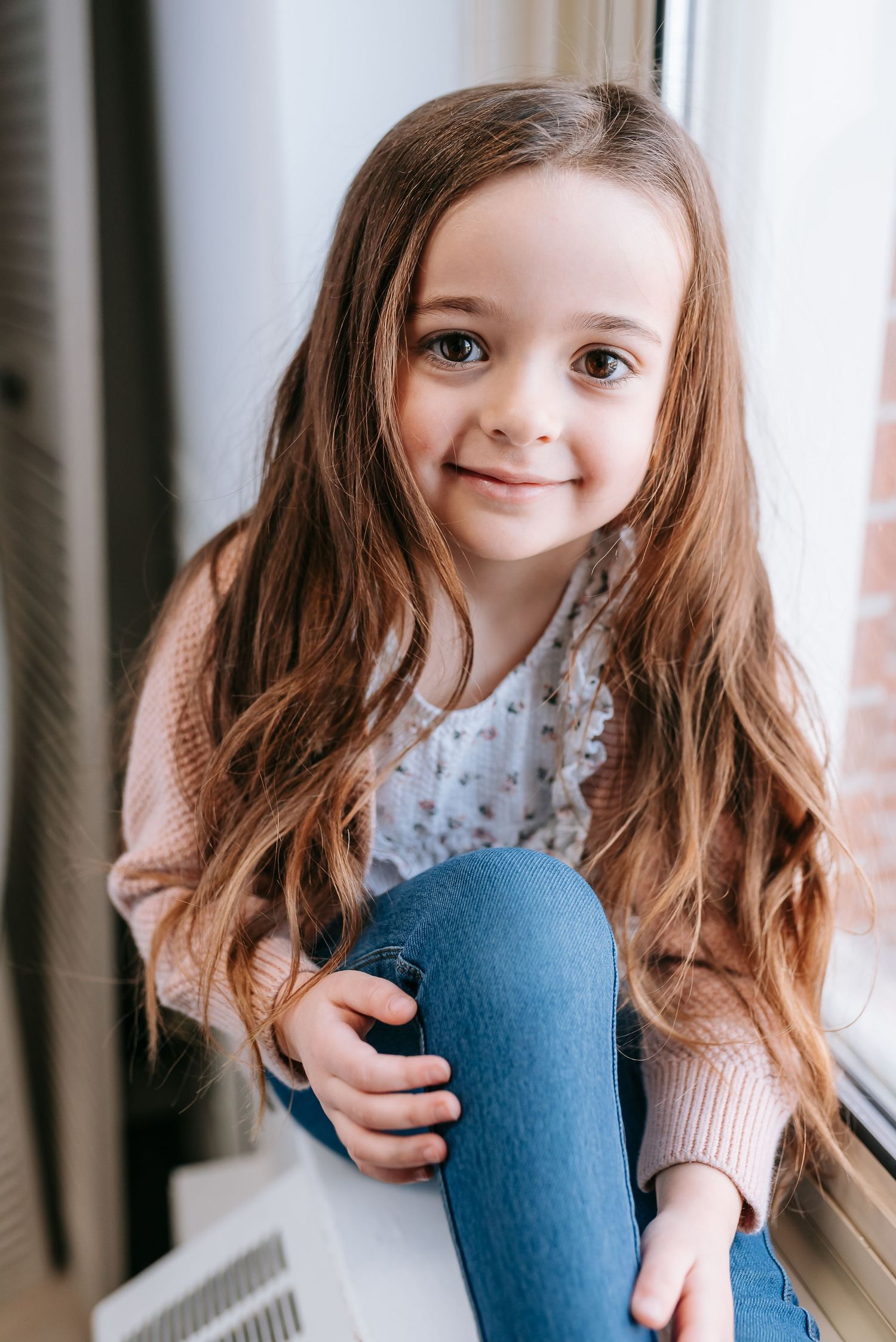 Window-lit portrait in casual attire with natural lighting.