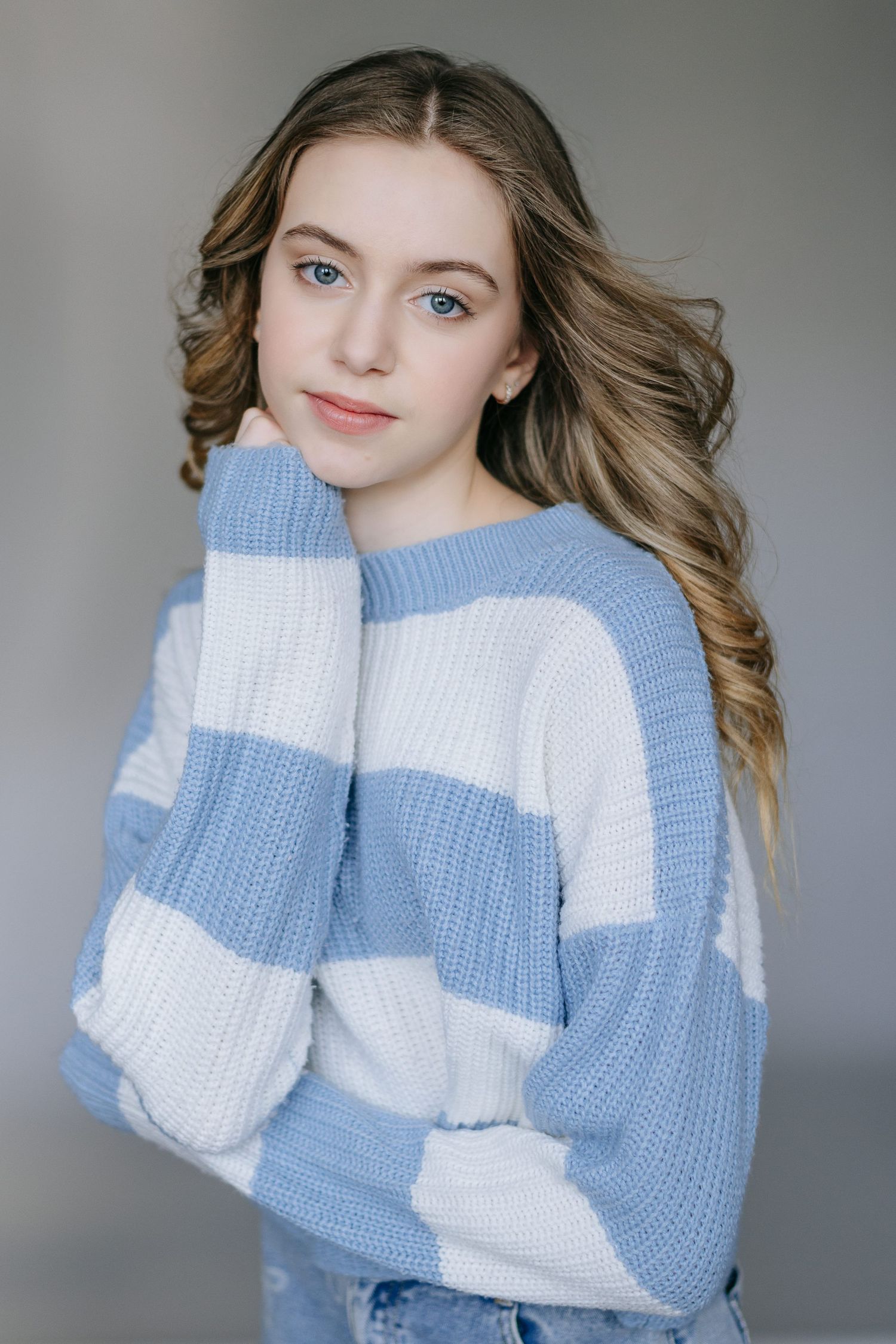 Model wearing cozy blue and white colorblock knit sweater in studio portraits against grey backdrop.